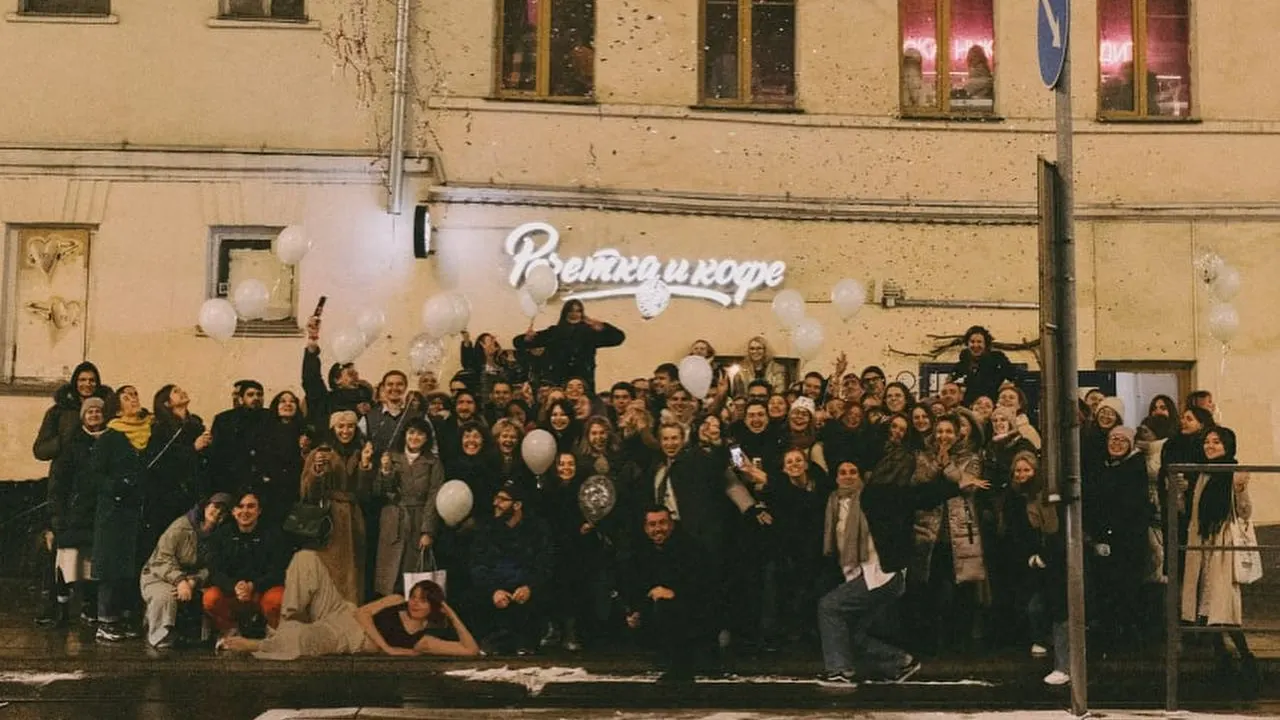 The farewell party — a crowd with white balloons under the shop sign